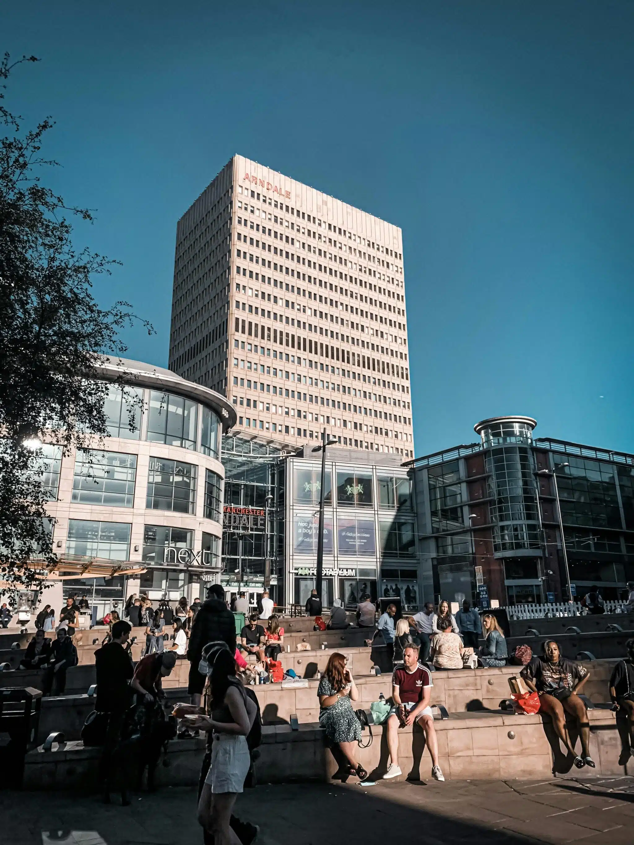 Urban plaza with people outside Manchester building.