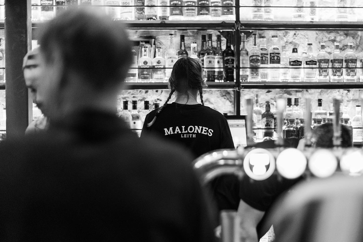 Bartender working in a busy bar with shelves
